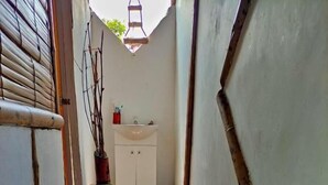 A narrow hallway with tiled flooring, a white sink, and a cabinet. - Hostal HALALIKU (Santa Marta)