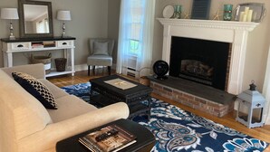 A living room with a fireplace, a sofa, a coffee table, and a bookshelf. - Beautiful Country Setting Near Newport (Portsmouth)