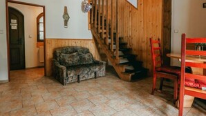 Ein Zimmer mit einer Holztreppe, einer Couch, einem Esstisch und einem Stuhl.