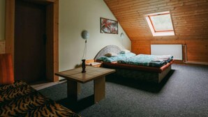 Ein gemütliches Schlafzimmer mit schrägen Wänden, einem Einzelbett, einem kleinen Tisch und einem Fenster mit Blick.