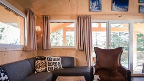 A cozy cabin interior with a sofa, a wooden coffee table, and a leather chair.