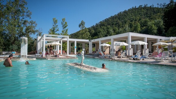 A pool area with multiple lounge chairs and umbrellas, surrounded by a white pavilion structure. - Albergo Terme Sant'Egidio (Castelforte)