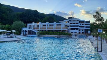 Piscina com um edifício moderno ao fundo.