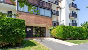 Un immeuble résidentiel moderne à plusieurs étages, doté d’une façade en briques, de grandes fenêtres et de balcons.