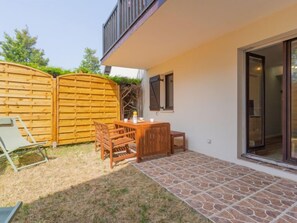A patio with a wooden table and chairs, a wooden fence, and a stone-tiled floor. - Cabourg Plage by Interhome (Cabourg)