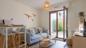Un salon moderne comprenant un canapé, une table à manger avec des chaises, une table basse et une grande fenêtre donnant sur un paysage verdoyant.