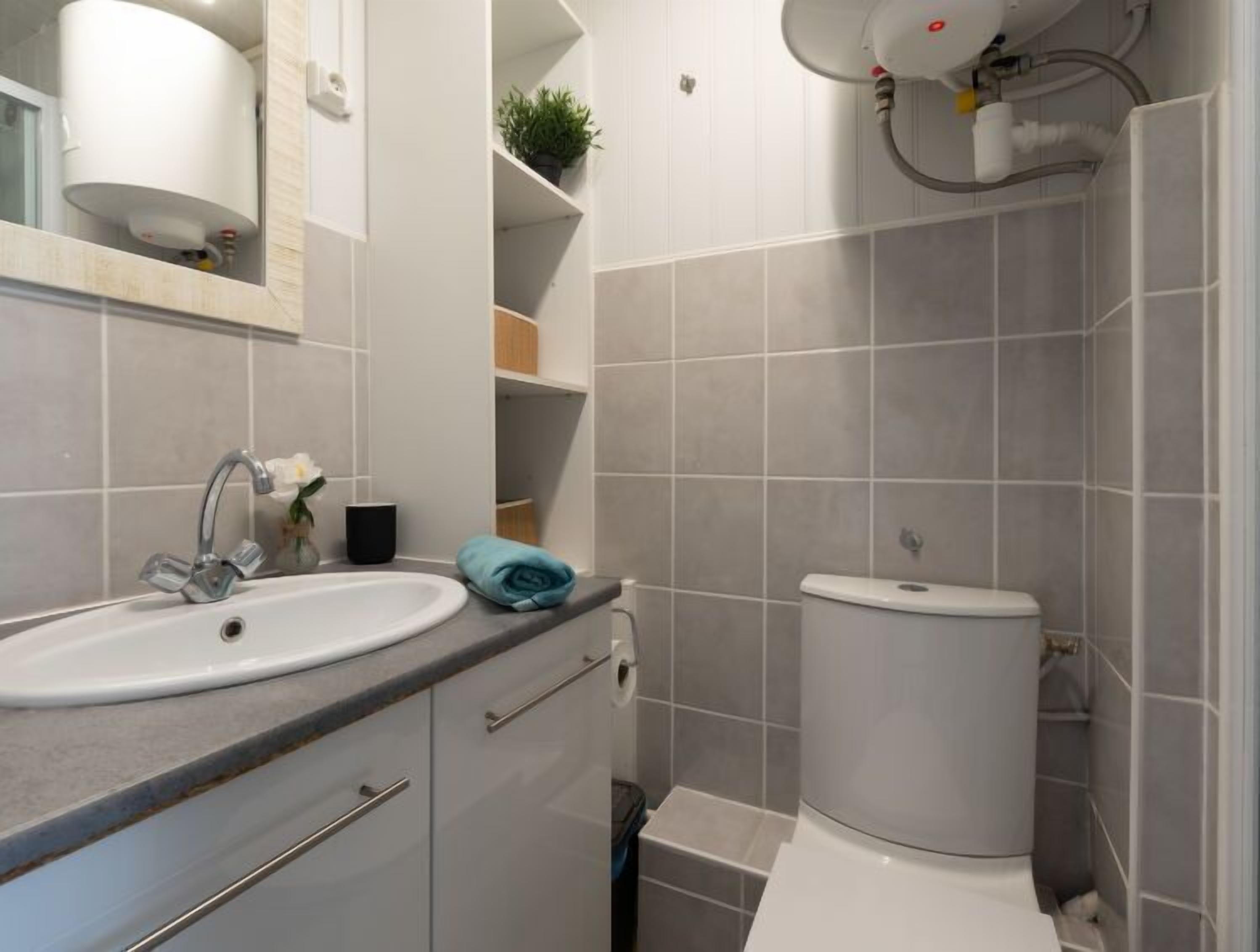 Een moderne badkamer met een wit wastafelmeubel, toilet en douche.