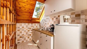 Una cocina compacta con vigas de techo de madera, un salpicadero de azulejos y un refrigerador empotrado.