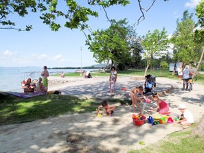 Enjoy a serene lakeside retreat with a sandy beach and lush surroundings, perfect for families to relax and play.
