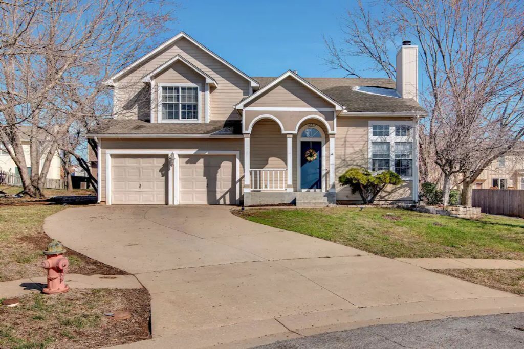 A two-story house with a garage, a front porch, and a small front yard.