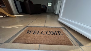 A welcome mat with the word "WELCOME" on a tiled floor. - Min Y Mor (Criccieth)