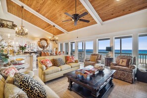 A spacious living area with a high ceiling, a ceiling fan, and a view of the ocean through large windows. - Beachfront Luxury Condo in Quiet Laguna Beach w/Amazing Views! Free Perks! (Panama City Beach)