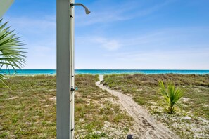 En strandpromenad som leder ner till havet, med en klar himmel.
