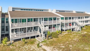 Een gebouw aan de kust met meerdere balkons en een strandlocatie.