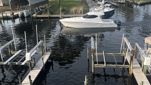 Un porto turistico con imbarcazioni ormeggiate, un capannone coperto per barche e un molo in legno.