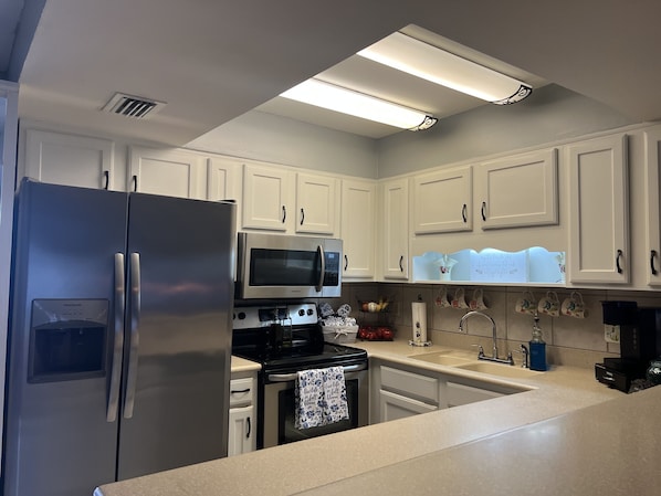 A kitchen with white cabinets, stainless steel appliances, and a countertop.