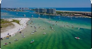 An aerial view of a beach with numerous boats, a pier, and high-rise buildings in the background.
