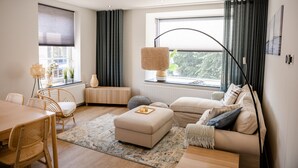 A modern living room with a sofa, ottoman, and dining table.