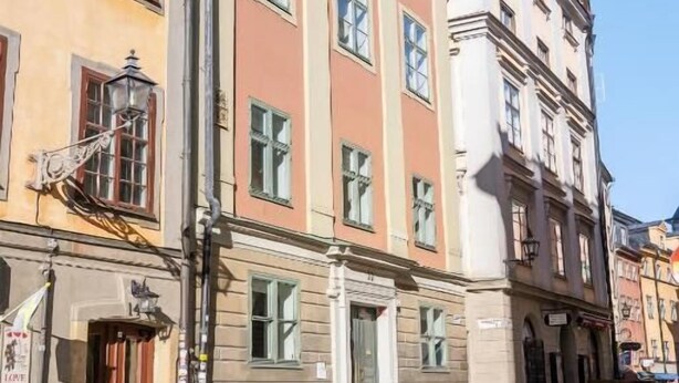 Un edificio de varios pisos con tienda en la planta baja, ventanas amplias y entrada en esquina.