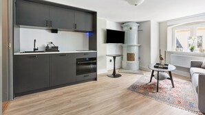 Cocina moderna con armarios oscuros, horno empotrado y una pequeña mesa redonda con un objeto decorativo.