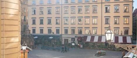 A cobblestone square with a historic building featuring a spire, a market stall, and a bicycle.