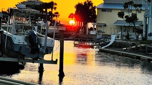 Ein Yachthafen mit anlegenden Booten, im Hintergrund ein Sonnenuntergang und ein Gebäude mit geneigtem Dach.