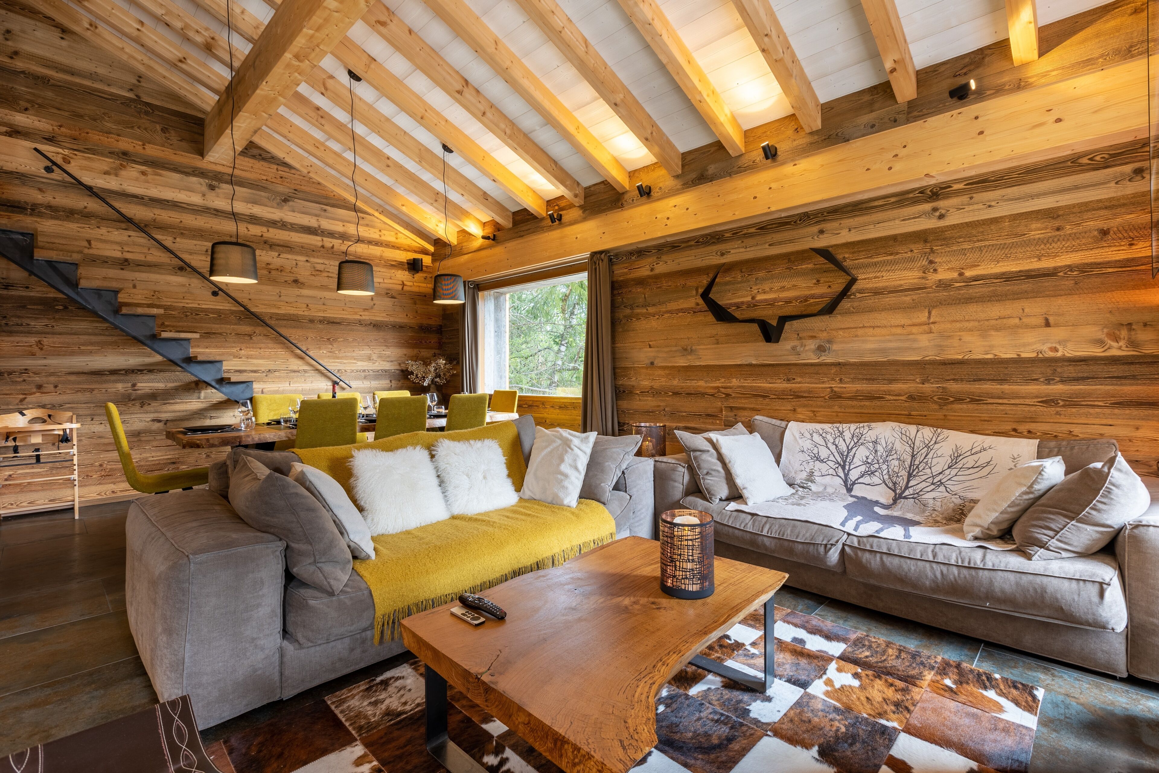Een gezellig cabin interieur met een houten plafond, twee banken, een salontafel en een trap.