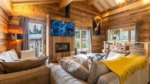 Ein gemütliches Blockhaus-Interieur mit einem großen Fernseher, bequemen Sitzgelegenheiten und einem Kamin.