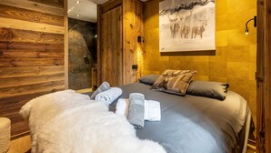 Ein modernes Hotelzimmer mit einem großen Bett, Holzvertäfelungen, einem Wandbild von Hirschen und ordentlich gefalteten Handtüchern.