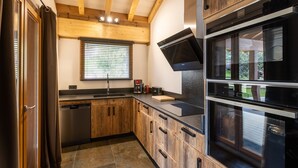 Eine moderne Küche mit Holzausstattung, einem eingebauten Backofen und einem Fenster mit Jalousien.