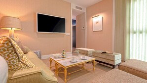 A hotel room with a sofa, a small table with cups and a book, a television, and a window with curtains. - Genteel Home Betis XVII (Seville)