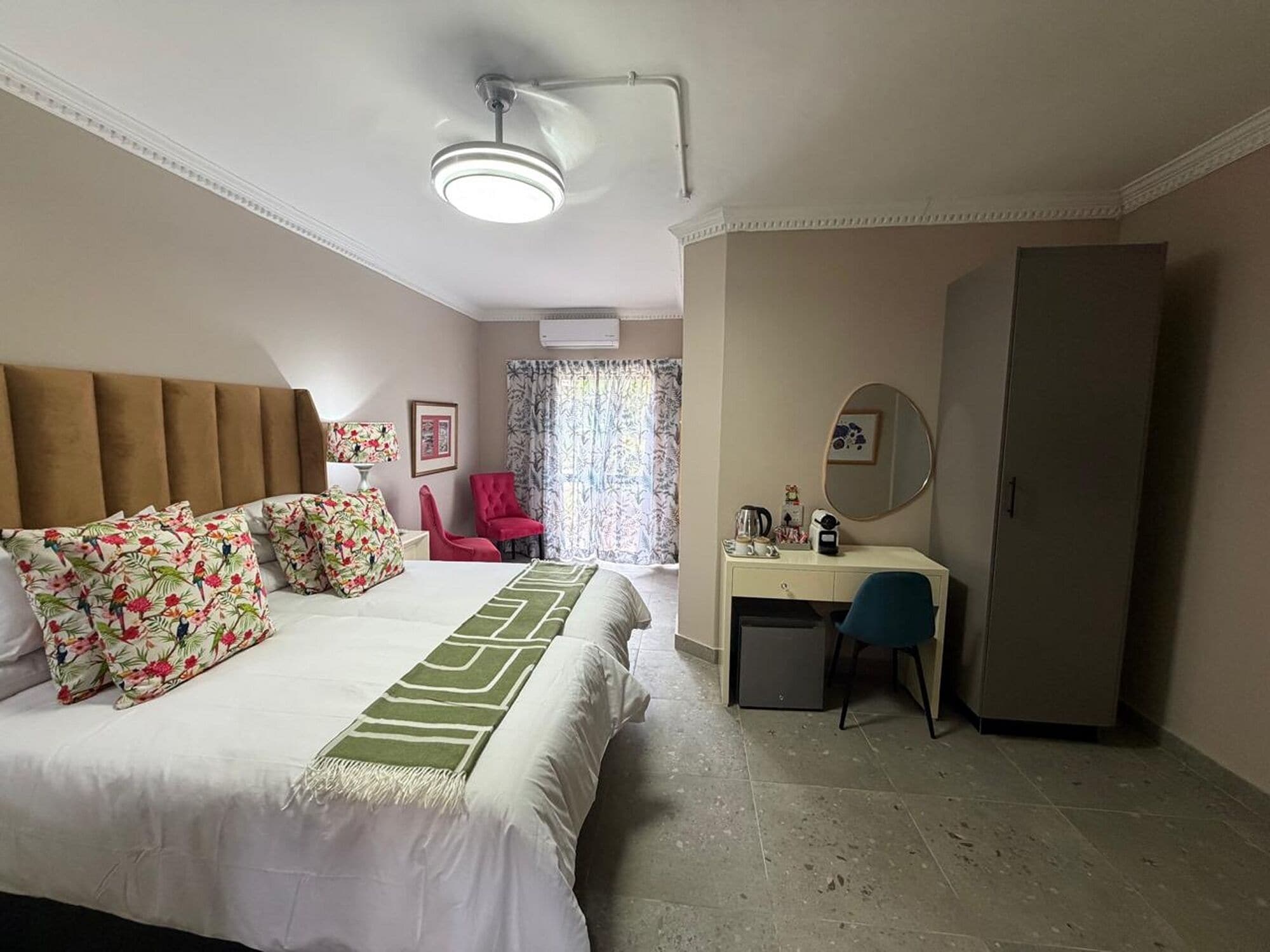 A hotel room with a bed, a desk, a chair, a wardrobe, and a ceiling fan.