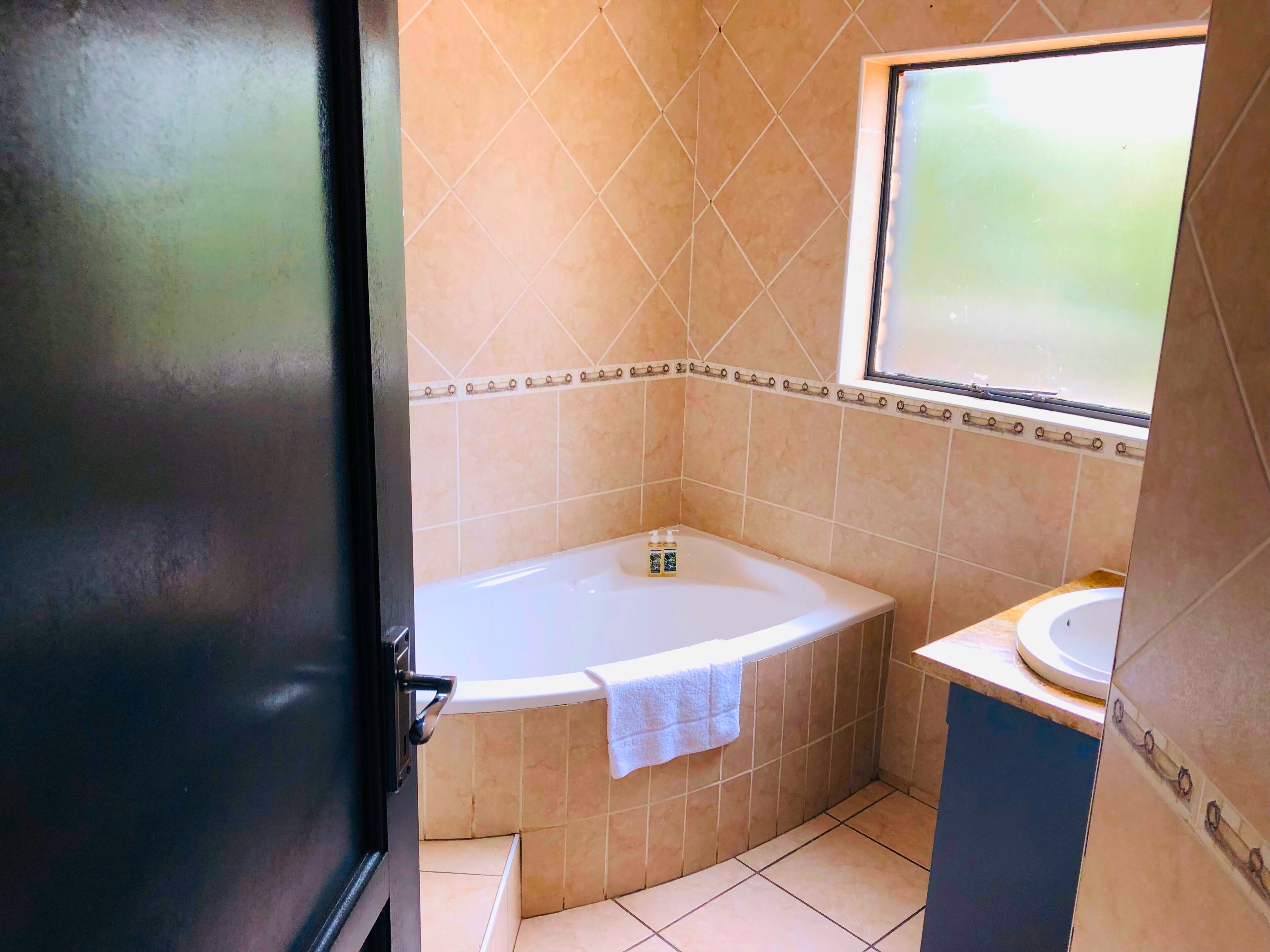 A bathroom with a bathtub, a sink, and a window.