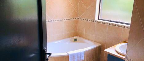 A bathroom with a bathtub, a sink, and a window.