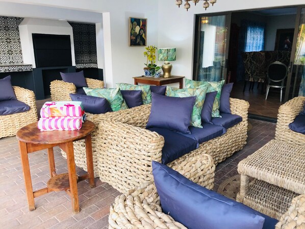 Un rincón acogedor con mobiliario de mimbre, una mesita con lámpara y una planta decorativa.