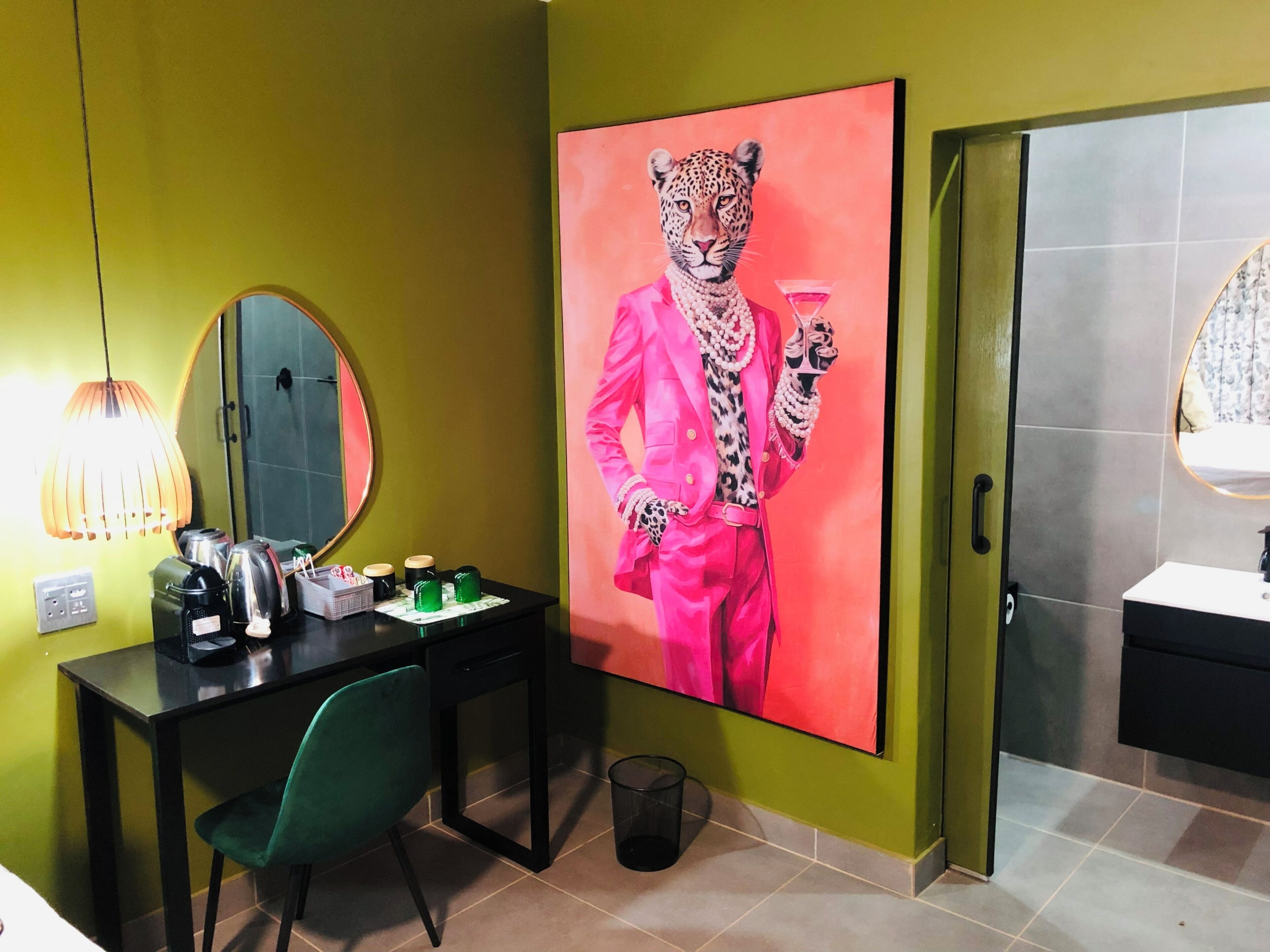 Une pièce comprenant un bureau, une chaise et un grand tableau représentant un léopard portant un costume rose.