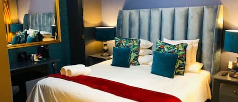 Una habitación de hotel con una cama grande, un espejo, un escritorio y una mesita de noche.