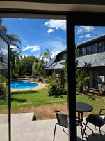 Una piscina con cielo azul despejado y palmeras al fondo.