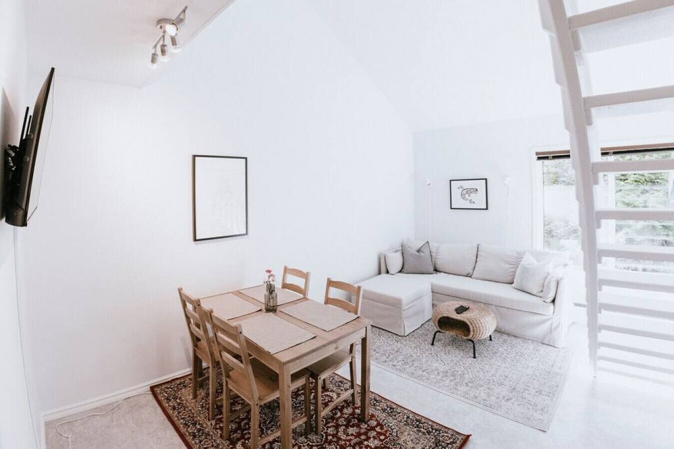 Una sala de estar moderna y minimalista con comedor, que incluye un sofá blanco, una mesita auxiliar y una mesa de comedor con sillas.