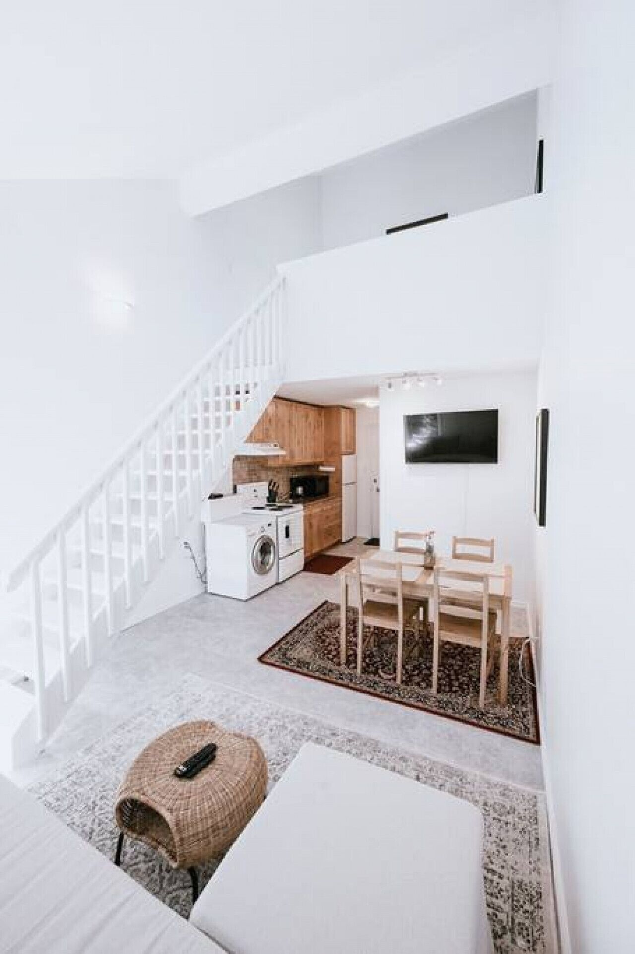 Un intérieur moderne et épuré, de couleur blanche, avec un escalier menant à une cuisine.