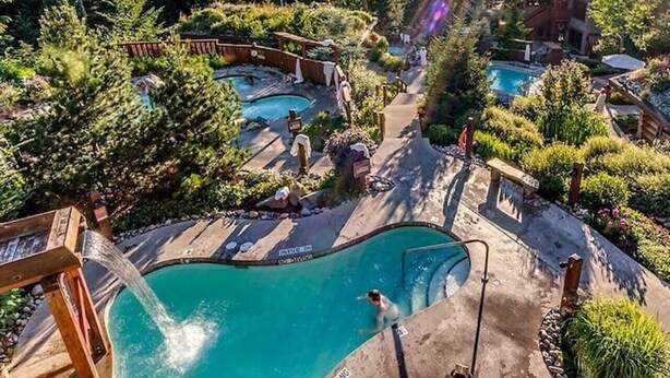 A resort with multiple swimming pools surrounded by dense forest and mountains in the background. - Mountainside 1BRM & Loft : Sleeps 4 ,Free Parking, Near Lakes, Restaurants & Shops! (Whistler)