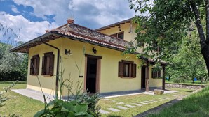 Une maison à deux étages avec une façade jaune, des éléments décoratifs en pierre et un toit recouvert de tuiles.