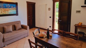 Un coin repas avec une table en bois, des chaises, un tableau au mur et une fenêtre avec des rideaux.