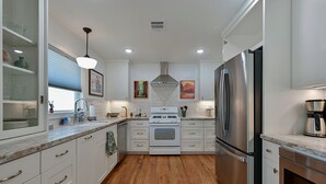 A modern kitchen with white cabinetry, a stainless steel refrigerator, a built-in oven, and a wooden floor. - Visiting professor?  New to area?  Perfect for you! (College Station)