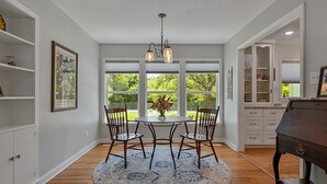 A dining area with a round table, chairs, a chandelier, and a view of greenery outside. - Visiting professor?  New to area?  Perfect for you! (College Station)