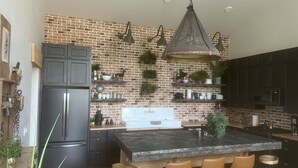 A modern kitchen with a brick backsplash, black cabinets, and a central island with bar stools.