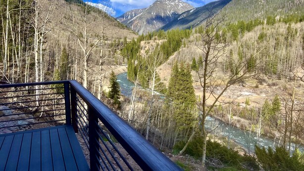 A wooden deck overlooking a mountainous landscape with a river.