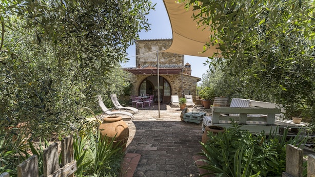 A courtyard with a stone pathway, outdoor furniture, and potted plants. - Casa Anita (Castellina in Chianti)
