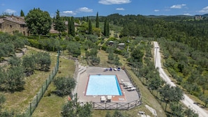 A rectangular swimming pool surrounded by a fenced area with lounge chairs and a paved deck. - Casa Anita (Castellina in Chianti)