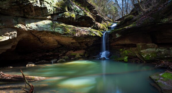 A waterfall in a rocky gorge with clear water and moss-covered rocks.